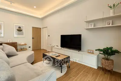 Modern living room with sleek furniture and stylish decor, featuring a large TV and elegant lighting.