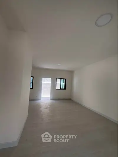 Spacious empty room with natural light and modern flooring, ideal for customization.