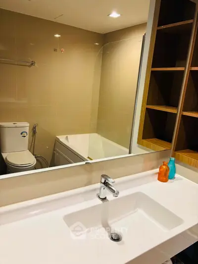 Modern bathroom with sleek fixtures and built-in shelving, featuring a bathtub and stylish sink.