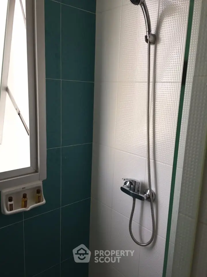 Compact bathroom shower area with window and modern fixtures.