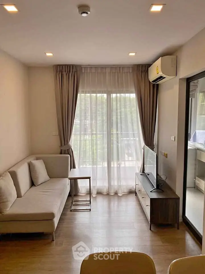 Modern living room with large window and balcony access, featuring a cozy sofa and sleek TV stand.