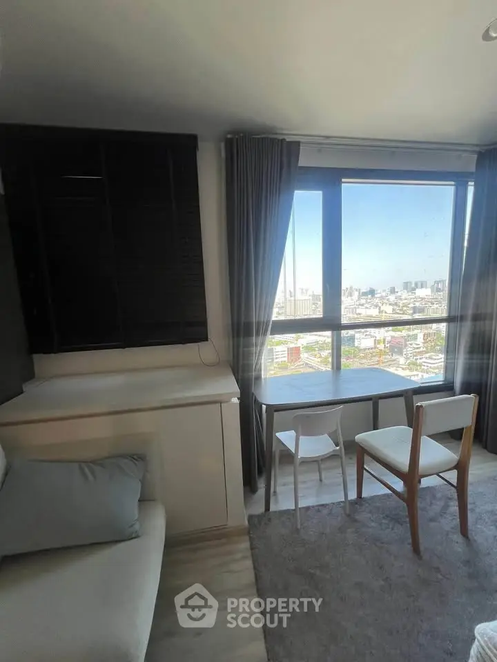 Modern living room with city view, featuring sleek furniture and large windows for natural light.
