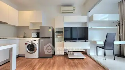 Modern open-layout living room with kitchen, featuring washing machine and sleek furniture.