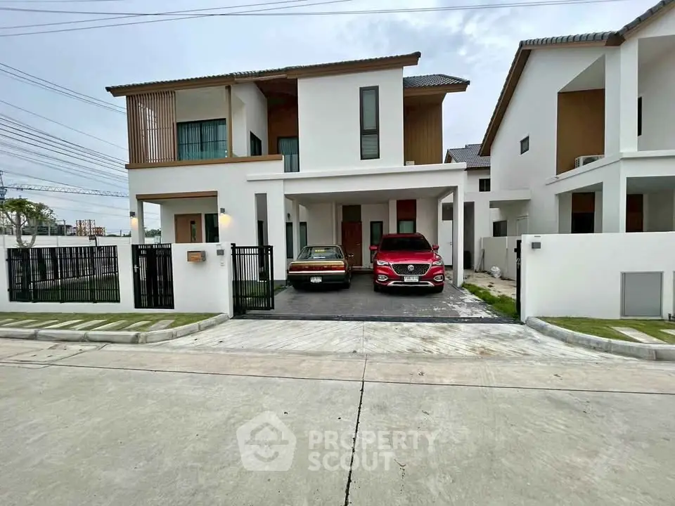 Modern two-story house with driveway and two cars parked, showcasing contemporary architecture.