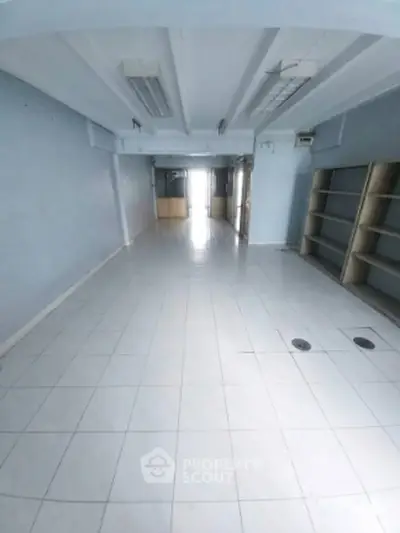 Spacious empty room with tiled flooring and built-in shelves, ideal for commercial use.