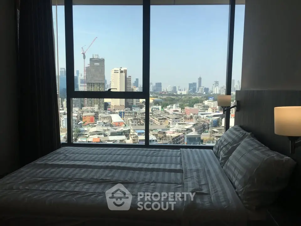 Modern bedroom with city view from large window, featuring cozy bed and stylish decor.