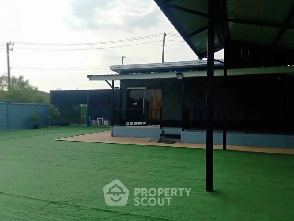 Spacious outdoor area with artificial grass and modern covered patio, perfect for gatherings.