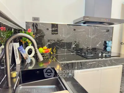 Modern kitchen with sleek black marble countertops and gas stove, featuring stylish decor and contemporary appliances.