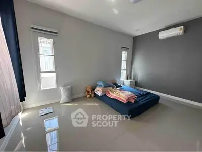 Spacious minimalist bedroom with natural light and modern air conditioning unit.