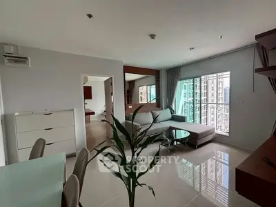 Modern living room with large windows and city view, featuring sleek furniture and open layout.