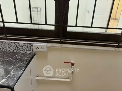 Modern kitchen with marble countertop and window view, featuring a convenient power outlet and water tap.