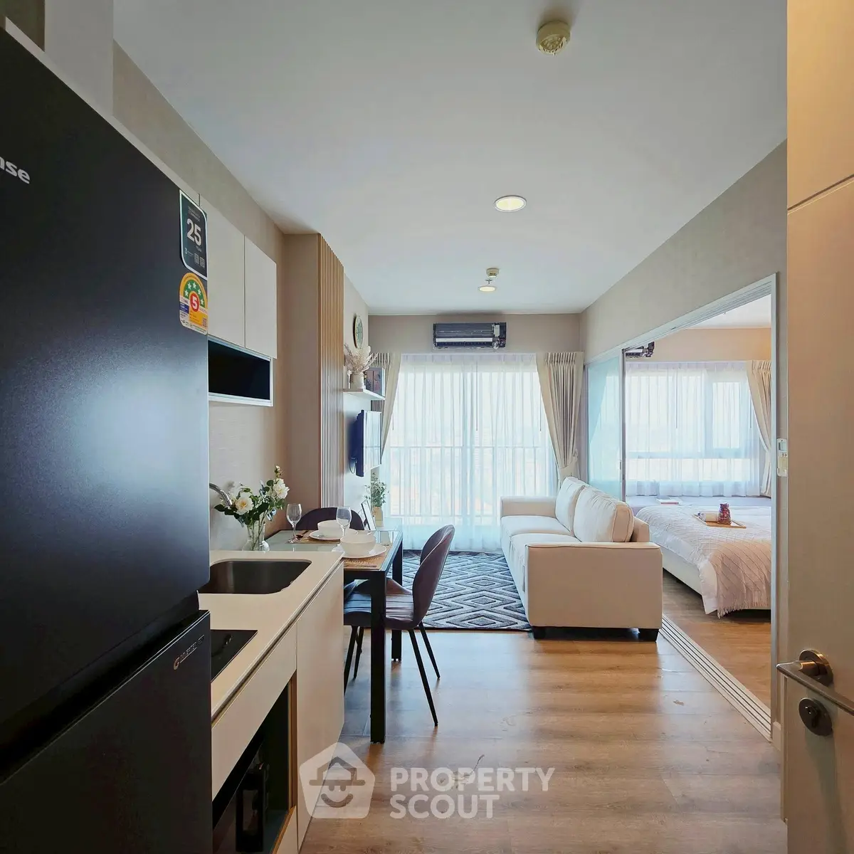 Modern open-plan living room with kitchen and bedroom, featuring stylish decor and natural light.