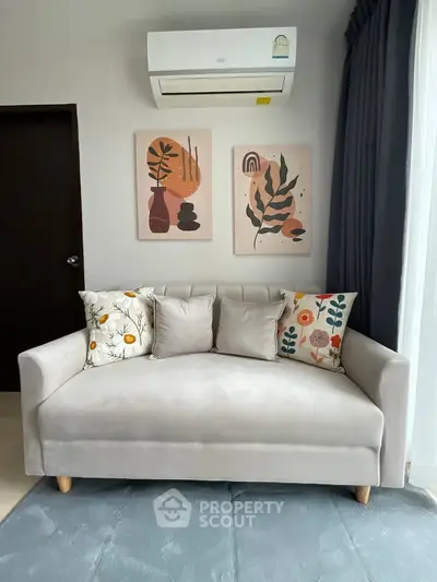 Modern living room with stylish sofa and wall art, featuring air conditioning and cozy decor.