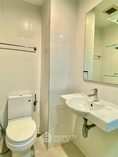 Modern bathroom with sleek white tiles and contemporary fixtures in a stylish real estate property.