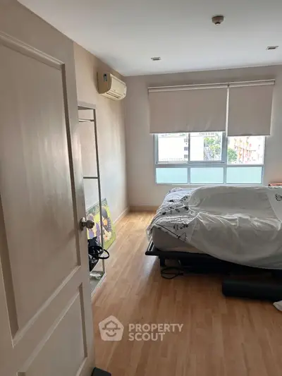 Cozy bedroom with wooden flooring and large window for natural light.