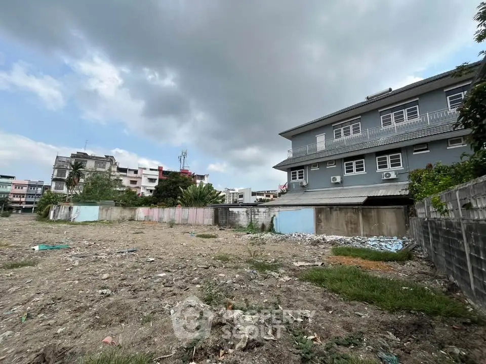 Vacant land plot with adjacent residential buildings, ideal for development opportunities.