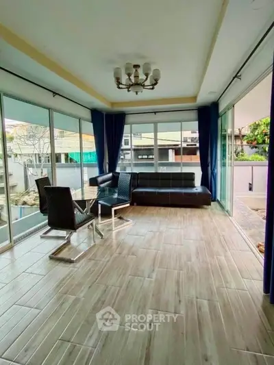 Spacious sunlit room with modern furniture and large windows offering a serene view.