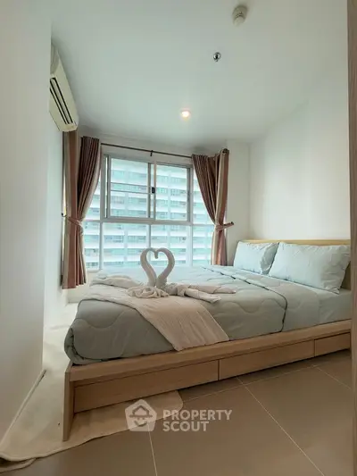 Cozy bedroom with modern decor and large window offering natural light.