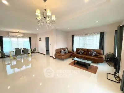 Spacious living room with elegant chandelier and modern furniture in a bright, airy setting.
