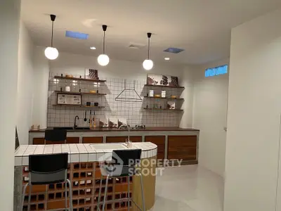 Modern kitchen with open layout, stylish lighting, and sleek tile backsplash