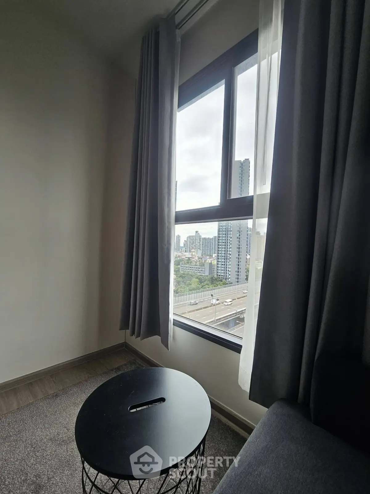 Modern apartment with city view from large window, featuring cozy interior and stylish furnishings.