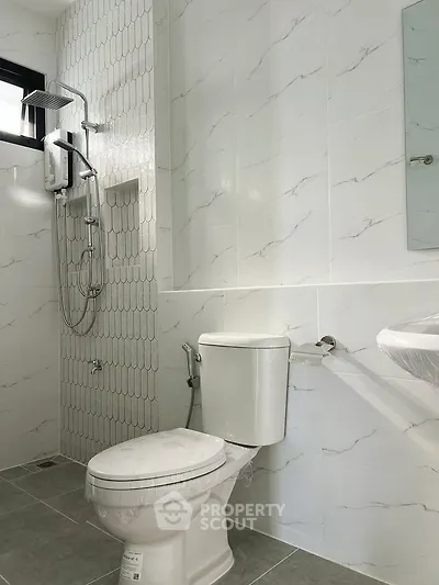 Modern bathroom with sleek shower and toilet in bright white tiles