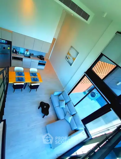 Modern open-plan living room with high ceilings and stylish kitchen in a contemporary apartment.