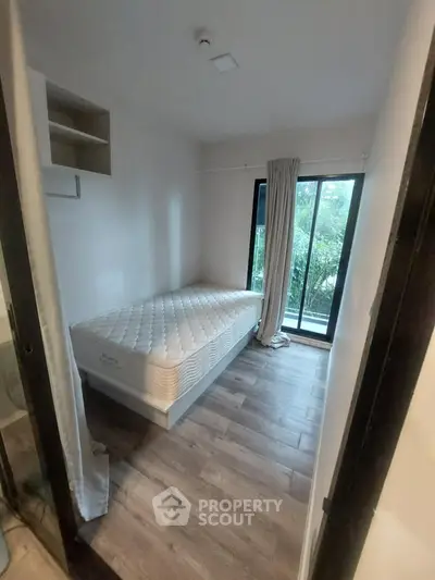 Cozy bedroom with single bed and large window overlooking greenery.