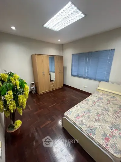 Spacious bedroom with wooden flooring and ample natural light