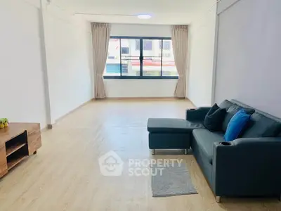 Spacious living room with modern sofa and large window offering natural light.
