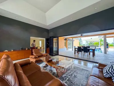 Luxurious open-plan living room with leather seating and poolside view