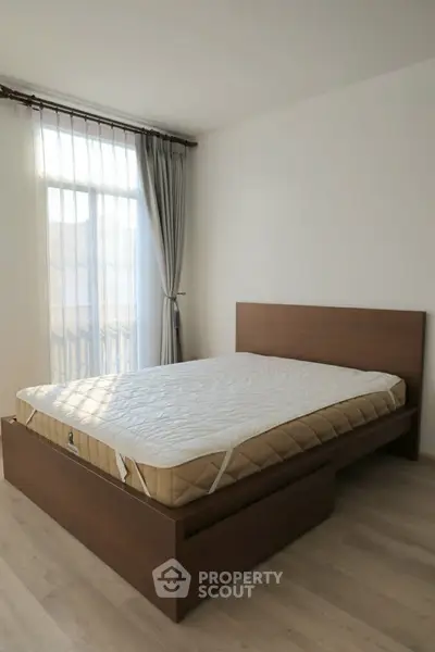 Spacious bedroom with natural light and modern wooden bed frame.