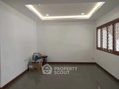 Spacious empty room with modern recessed lighting and large window, ideal for customization.