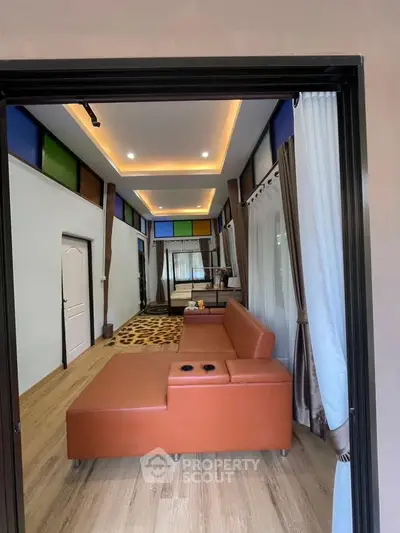 Spacious living room with modern decor and stylish lighting, featuring a comfortable leather sofa and elegant curtains.