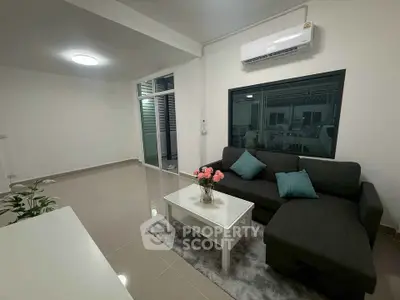 Modern living room with sleek sofa and air conditioning, featuring elegant decor and spacious layout.