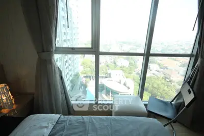 Modern bedroom with floor-to-ceiling windows offering stunning city views in a high-rise apartment.