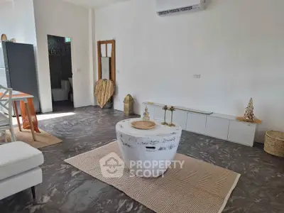 Modern living room with stylish decor and air conditioning, featuring a unique coffee table and sleek flooring.