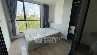 Bright bedroom with large window and city view, featuring a comfortable bed and modern design.