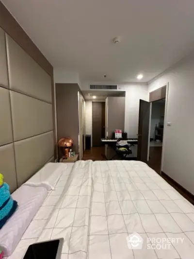 Spacious bedroom with large built-in wardrobe and warm lighting, leading to a cozy hallway and additional rooms, perfect for comfortable living.