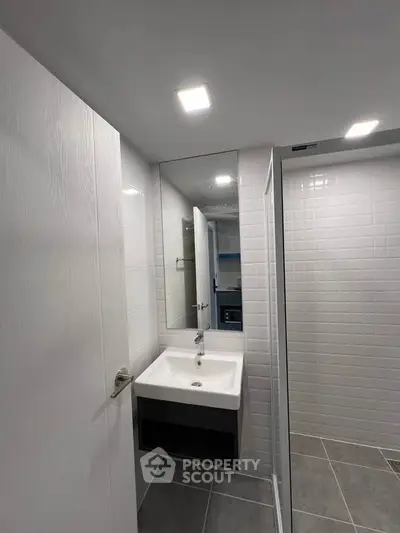 Modern bathroom with sleek sink and large mirror in contemporary apartment.