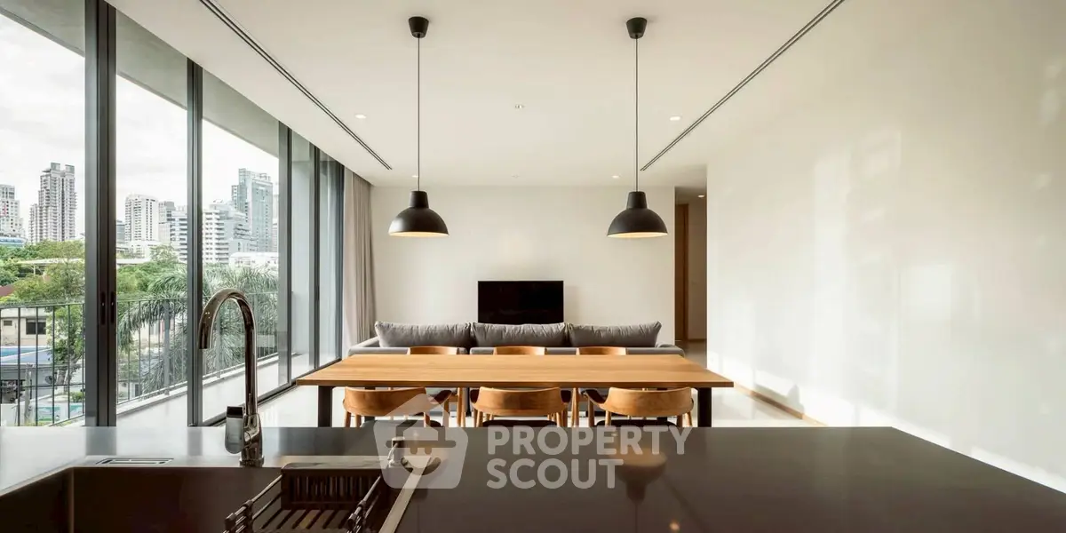 Modern open-plan living room with dining area and city view, featuring sleek design and ample natural light.