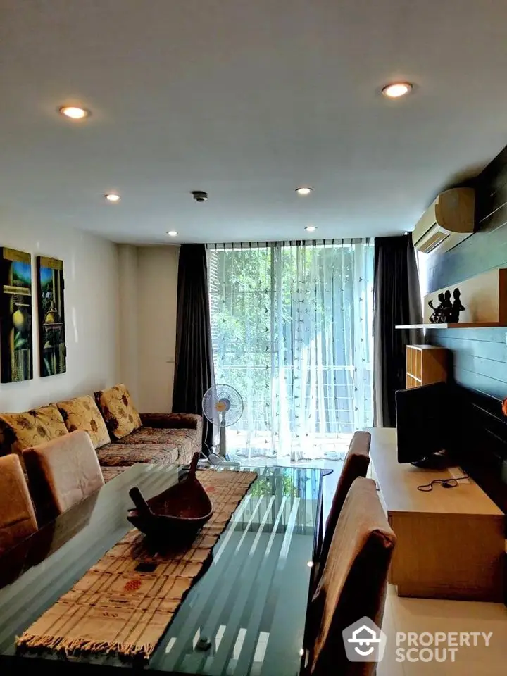 Spacious living room with modern decor and large glass table, perfect for entertaining guests.