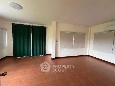 Spacious empty room with tiled flooring and large windows, perfect for customization.