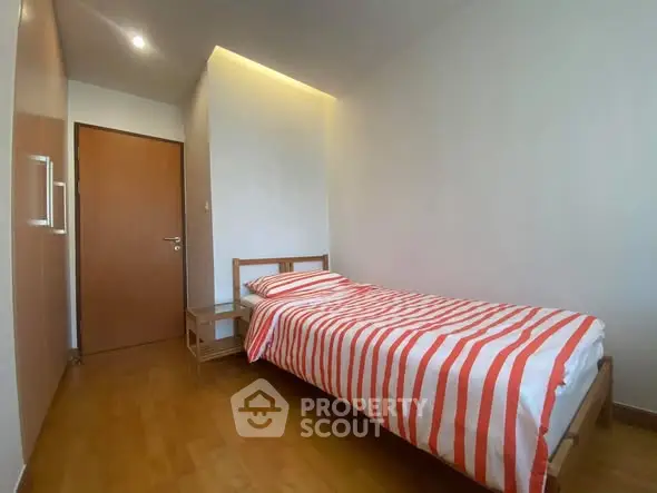 Cozy minimalist bedroom with wooden flooring and striped bedding