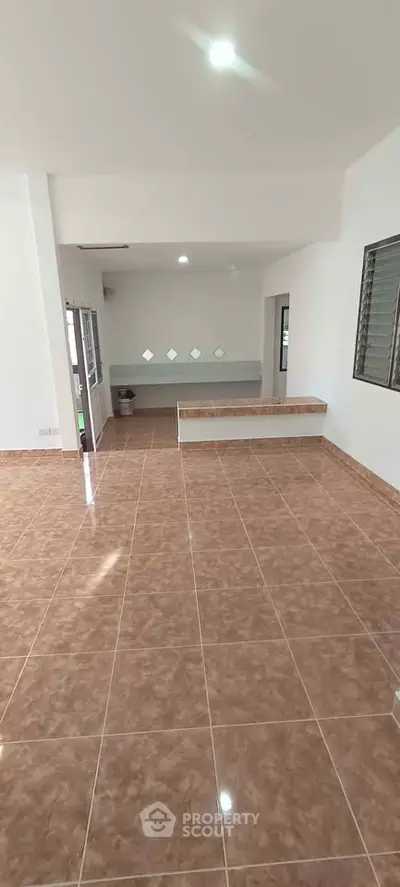 Spacious open-plan living area with tiled flooring and ample natural light.