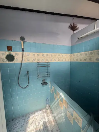 Charming vintage bathroom with blue tiles and shower area, perfect for retro lovers.