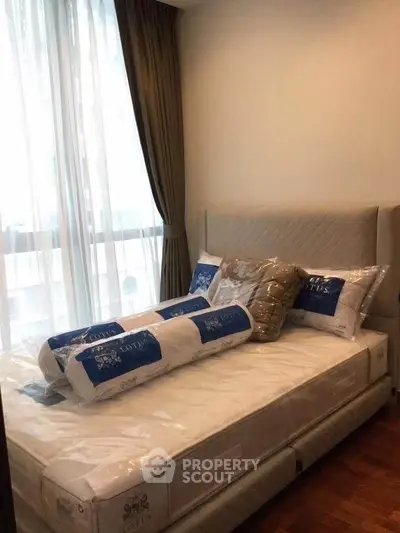 Cozy bedroom with large window and elegant curtains, featuring a plush bed with new bedding.