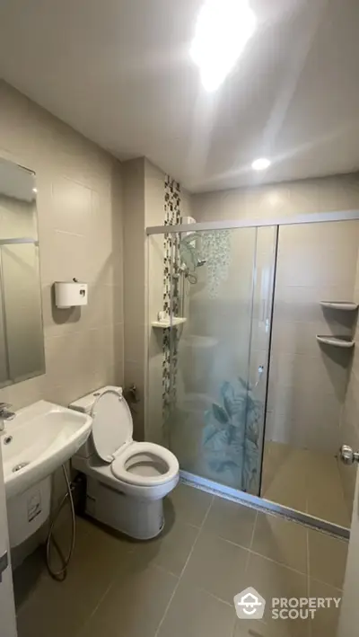 Modern bathroom with glass shower and sleek fixtures in contemporary home.