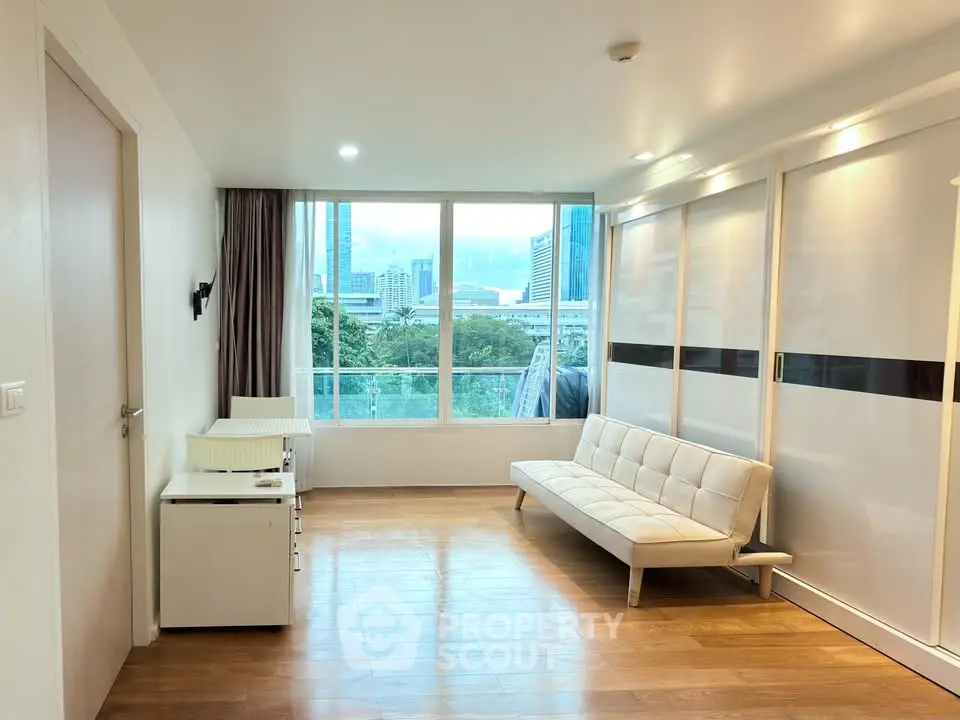 Spacious living room with city view and modern furnishings in high-rise apartment.