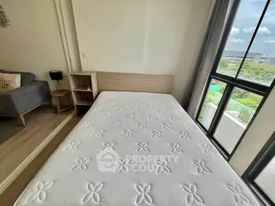 Bright bedroom with large window and modern furnishings, offering a serene view.